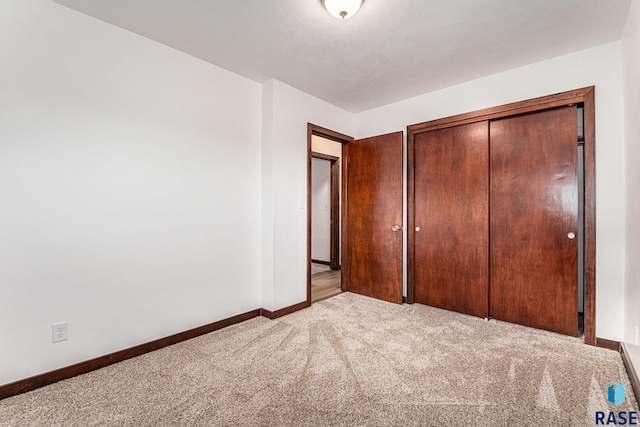 unfurnished bedroom featuring light carpet and a closet