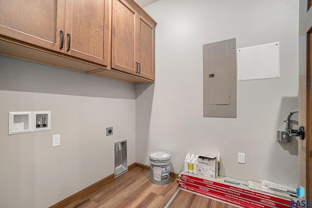 clothes washing area featuring electric panel, cabinets, washer hookup, hookup for an electric dryer, and light wood-type flooring