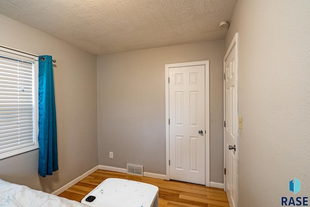 unfurnished bedroom featuring wood-type flooring and a textured ceiling