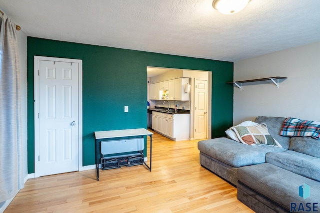 living room with sink, a textured ceiling, and light wood-type flooring