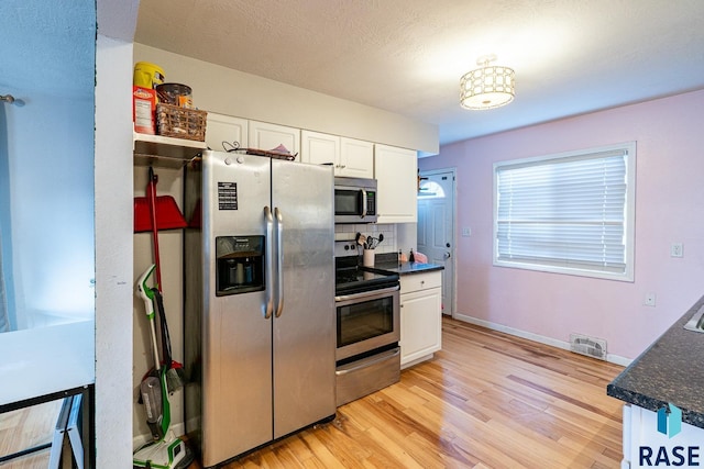 kitchen with white cabinetry, tasteful backsplash, stainless steel appliances, and light hardwood / wood-style flooring