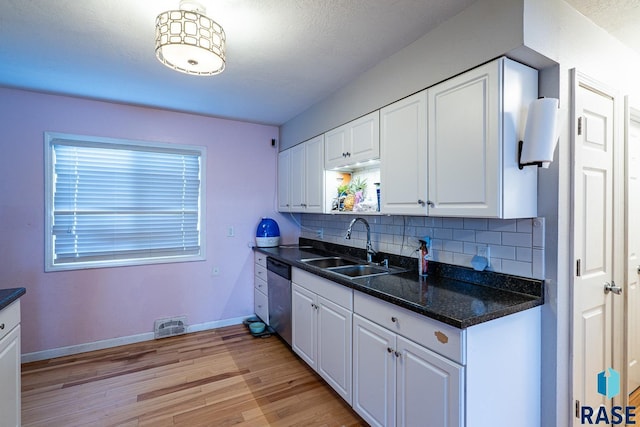 kitchen featuring decorative light fixtures, sink, white cabinets, backsplash, and stainless steel dishwasher