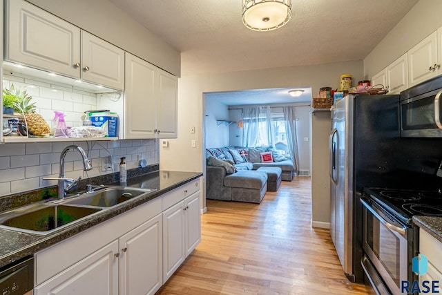 kitchen with sink, white cabinets, decorative backsplash, stainless steel appliances, and light wood-type flooring