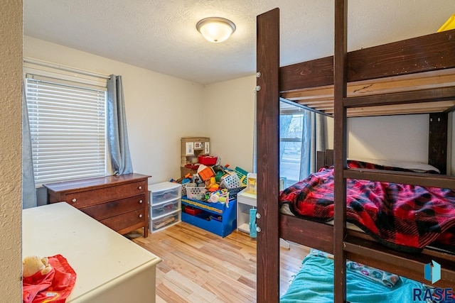 bedroom featuring multiple windows, wood-type flooring, and a textured ceiling