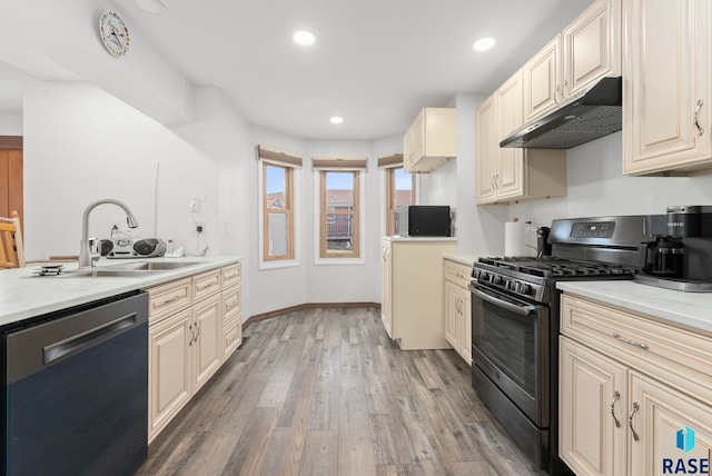 kitchen with sink, wood-type flooring, stainless steel dishwasher, black gas range, and cream cabinetry