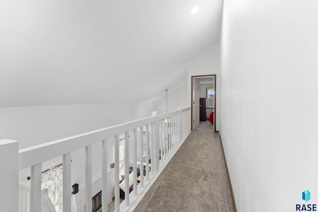 corridor with lofted ceiling and light colored carpet