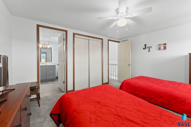 bedroom featuring ensuite bathroom, light colored carpet, ceiling fan, and a closet