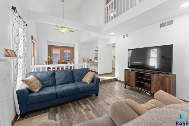 living room featuring a towering ceiling, french doors, ceiling fan, and hardwood / wood-style flooring