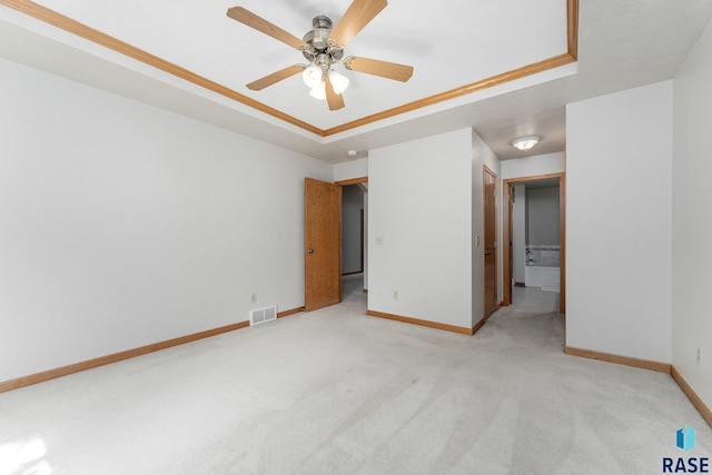 unfurnished bedroom featuring crown molding, light colored carpet, ceiling fan, and a tray ceiling