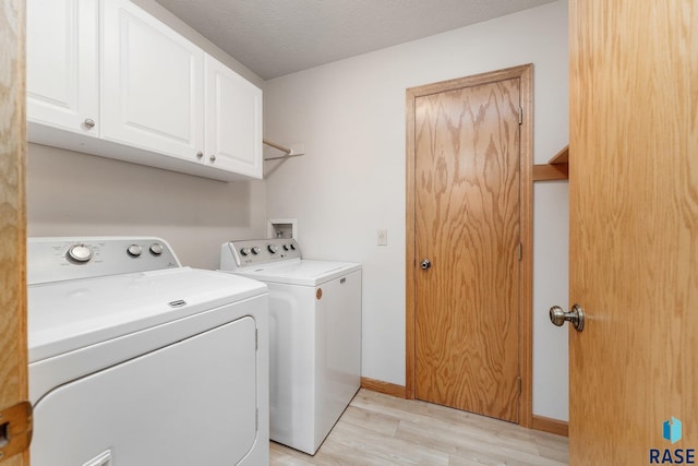 washroom featuring cabinets, washing machine and clothes dryer, a textured ceiling, and light hardwood / wood-style flooring