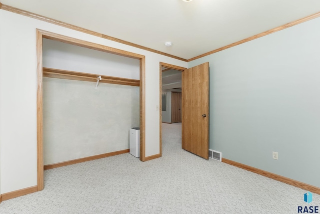 unfurnished bedroom featuring crown molding, light colored carpet, and a closet