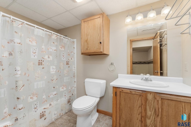 bathroom featuring vanity, toilet, and a drop ceiling