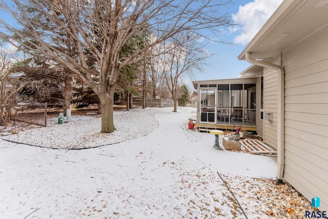 yard covered in snow featuring a sunroom