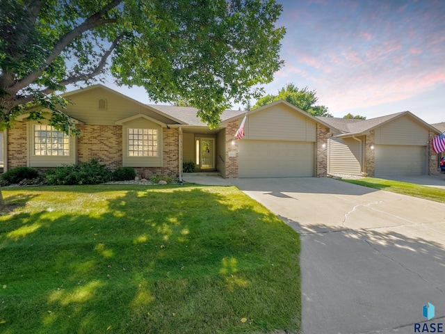 single story home featuring a garage and a lawn