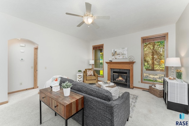 carpeted living room with a premium fireplace, a textured ceiling, and ceiling fan