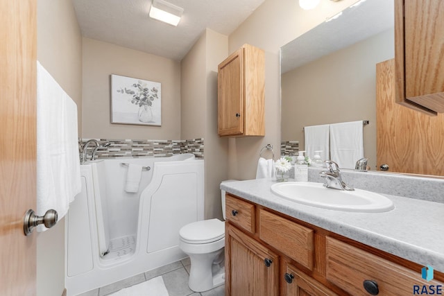 bathroom featuring tile patterned flooring, vanity, a textured ceiling, and toilet