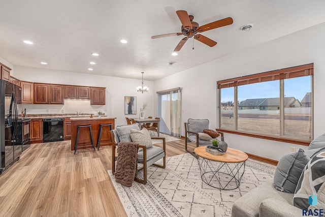 living room with sink, ceiling fan with notable chandelier, and light hardwood / wood-style floors