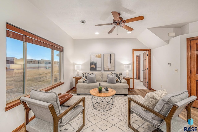 living room with ceiling fan, lofted ceiling, and light wood-type flooring