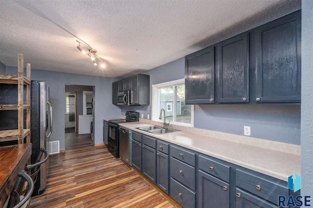 kitchen featuring dark hardwood / wood-style floors, rail lighting, sink, black appliances, and a textured ceiling