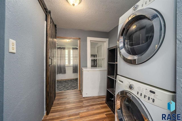 washroom featuring stacked washer and clothes dryer, hardwood / wood-style floors, and a textured ceiling