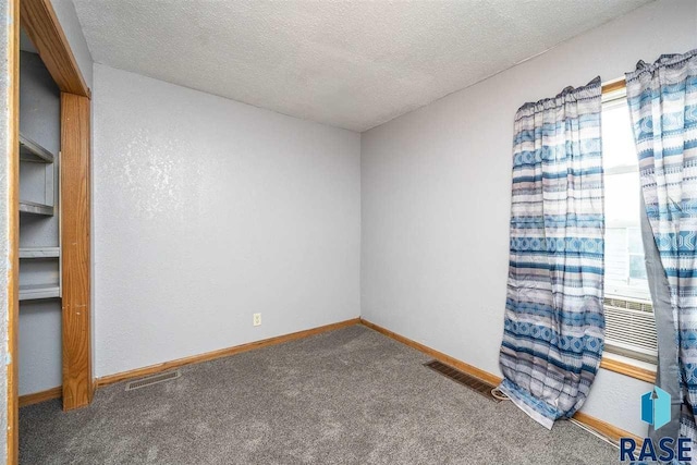 carpeted empty room featuring a textured ceiling