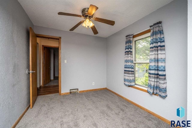 carpeted spare room with ceiling fan and a textured ceiling