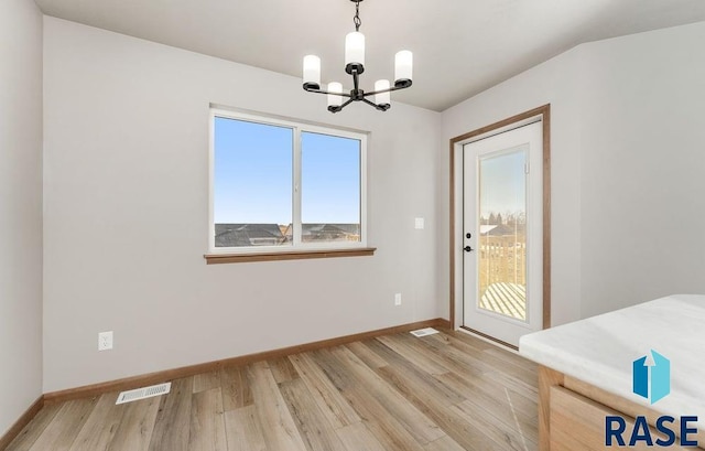 unfurnished dining area featuring light hardwood / wood-style flooring and a chandelier