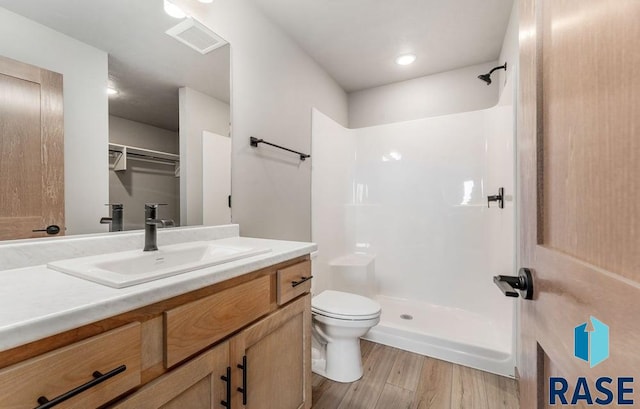 bathroom featuring vanity, hardwood / wood-style flooring, toilet, and walk in shower