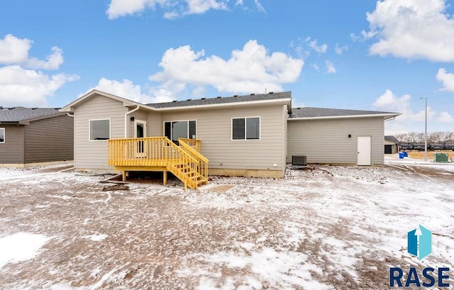 snow covered rear of property with a deck