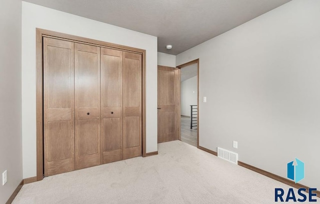 unfurnished bedroom with light colored carpet and a closet