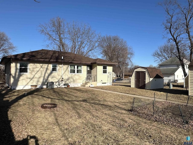 rear view of house with a storage shed and a yard