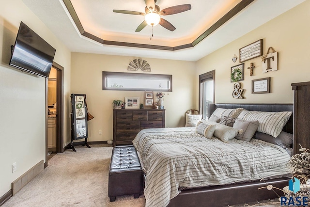 bedroom featuring a raised ceiling, light colored carpet, and ceiling fan