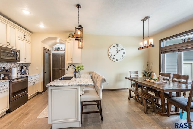 kitchen with sink, light stone counters, decorative light fixtures, range with electric stovetop, and kitchen peninsula