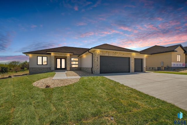 prairie-style home featuring a garage and a yard