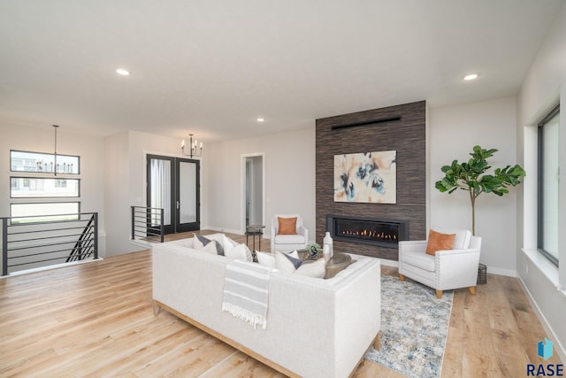 living room featuring a large fireplace, an inviting chandelier, and light hardwood / wood-style flooring