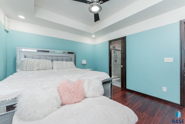 bedroom with dark wood-type flooring, a raised ceiling, and ceiling fan