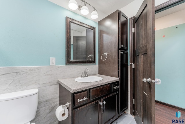 bathroom featuring vanity, toilet, and tile walls