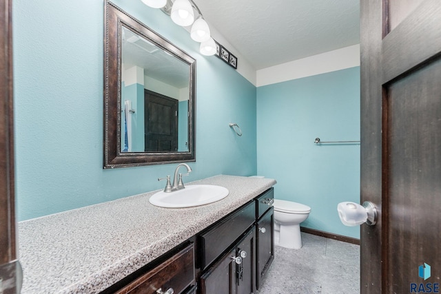 bathroom with vanity, toilet, and a textured ceiling