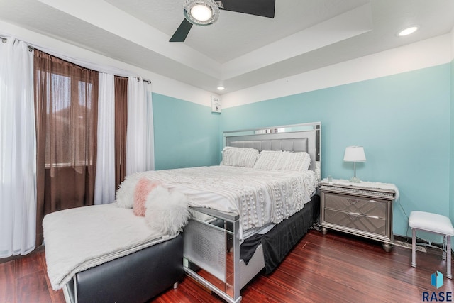 bedroom featuring ceiling fan, a tray ceiling, and dark hardwood / wood-style flooring