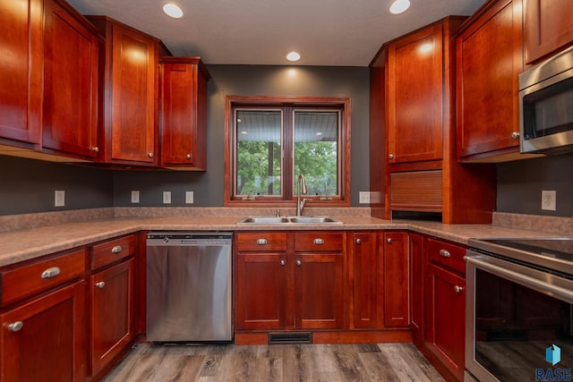 kitchen with stainless steel appliances, sink, and light wood-type flooring