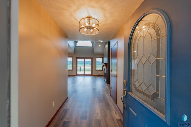 hall with a notable chandelier, dark wood-type flooring, and a textured ceiling