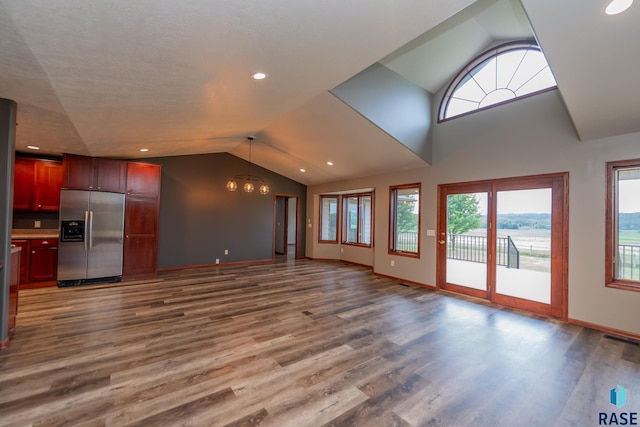 unfurnished living room featuring an inviting chandelier, wood-type flooring, and vaulted ceiling