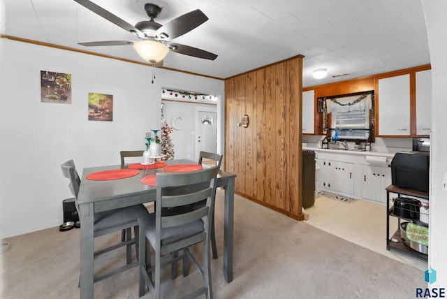 carpeted dining area with crown molding and wood walls