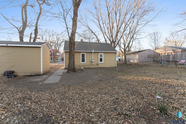 back of property featuring a trampoline and an outdoor structure