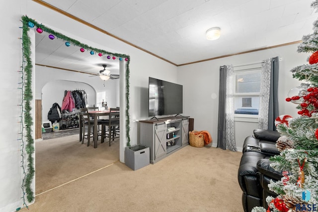 living room with crown molding, ceiling fan, and light carpet