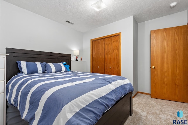 carpeted bedroom featuring a closet and a textured ceiling