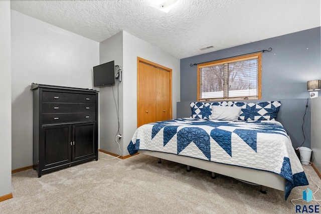 carpeted bedroom featuring a textured ceiling and a closet