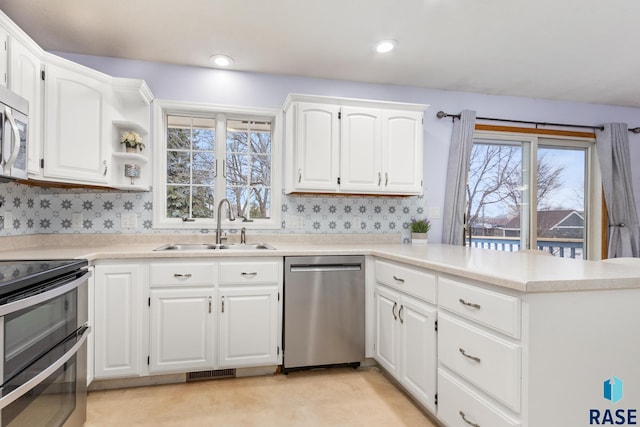 kitchen featuring stainless steel appliances, white cabinetry, sink, and kitchen peninsula