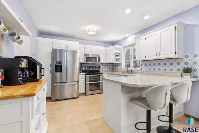 kitchen with white cabinetry, stainless steel appliances, and kitchen peninsula