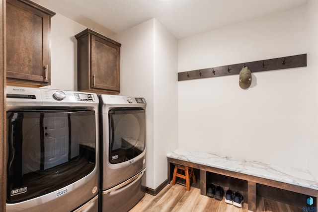 laundry room with cabinets, washer and dryer, and light wood-type flooring